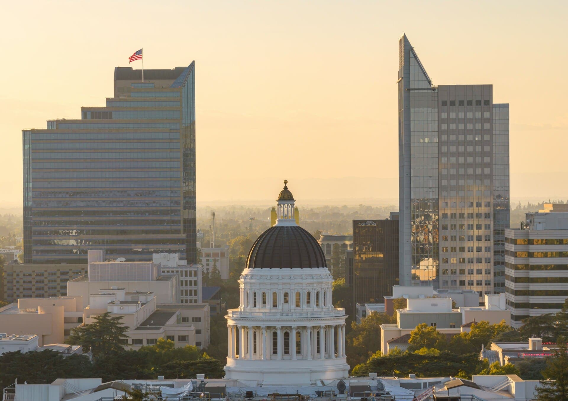 The California State Capitol dome at golden hour, with the downtown Sacramento skyline rising behind it